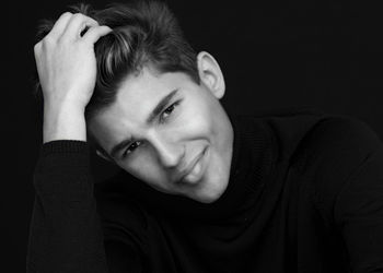 Portrait of young man against black background