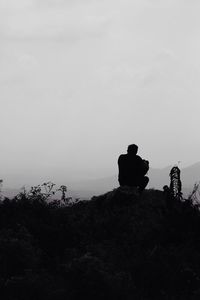 Rear view of woman sitting on rock