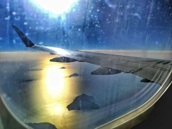 Close-up of airplane wing over landscape against sky