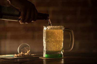 Close-up of hand pouring drink in glass