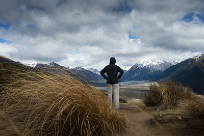 Rear view of man standing on field against sky