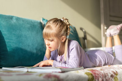 Portrait of girl using mobile phone while lying on bed at home