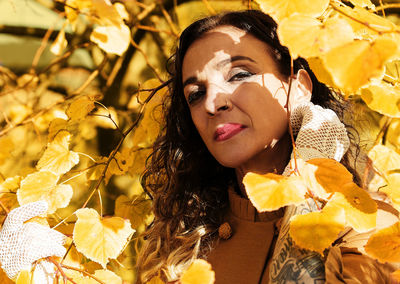 Portrait of woman standing amidst autumn leaves