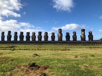 Statues on grass against sky