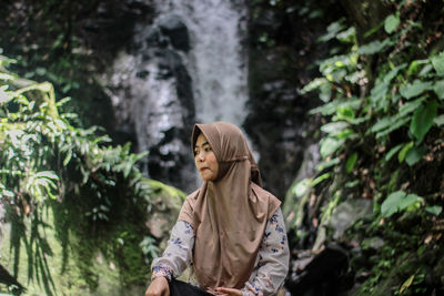 Woman sitting against waterfall