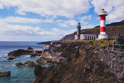 Lighthouse by sea against sky