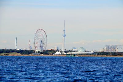 Ferris wheel by sea against sky