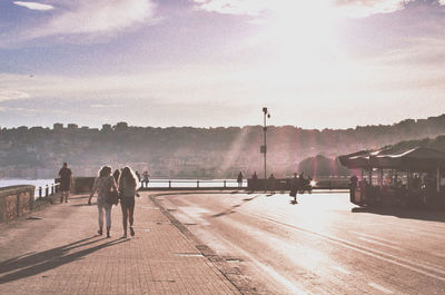 Rear view of women walking on sidewalk