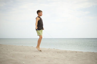 Boy on the beach with a skipping rope. lifestyle themes. healthy . sports and training by the sea.