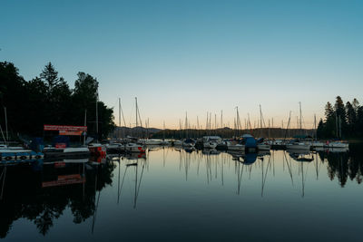 Sailboats moored at harbor against sky during sunset