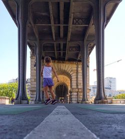 Rear view of a man walking in front of bridge