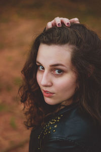 Close-up portrait of young woman with hand in hair