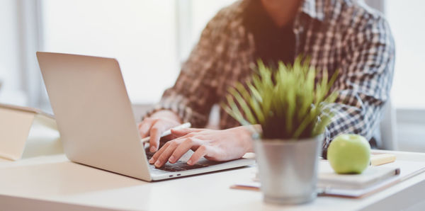 Midsection of man using laptop on table