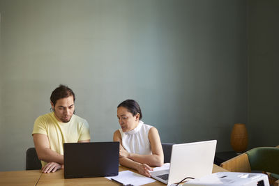 Coworkers in boardroom using laptop