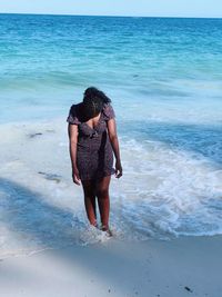 Rear view of woman standing at beach