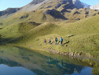 People walking on mountain by lake