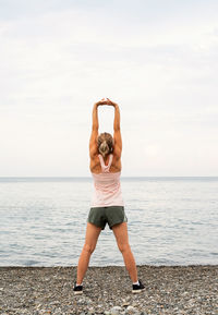 Full length rear view of woman standing on beach against sea