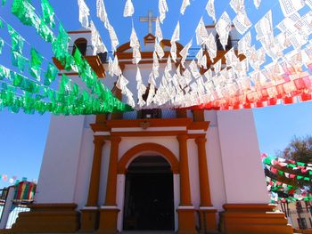 Low angle view of illuminated lanterns hanging by building against sky