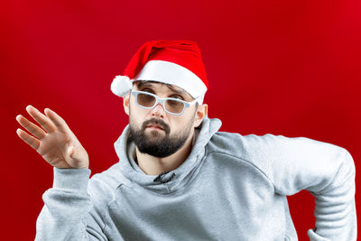 Portrait of young man wearing hat against red background