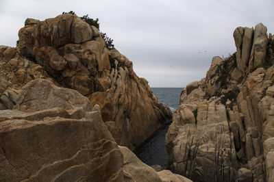 Rocks on sea shore against sky