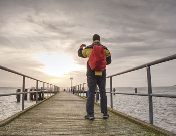 Rear view of man standing on bridge against sky