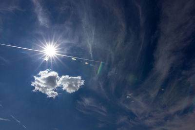 Low angle view of sunlight streaming through clouds