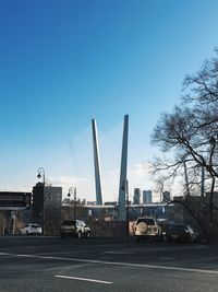 Cars on road by buildings against clear blue sky