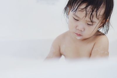 Shirtless girl playing with soap sud in bathroom