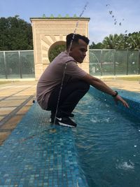 Boy in swimming pool against sky