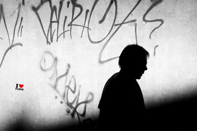 Silhouette person standing by text on wall