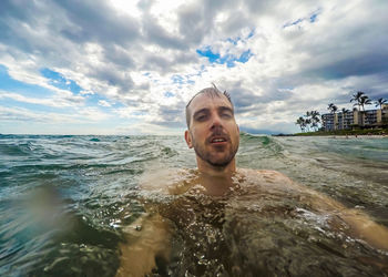 Portrait of young man in sea against sky