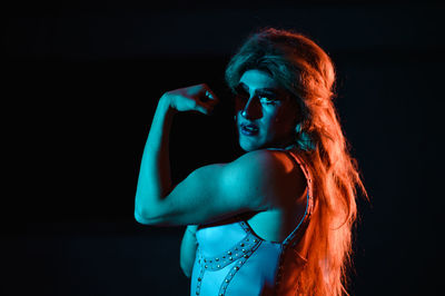 Portrait of young woman against black background