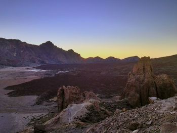 Scenic view of rocky mountains against clear sky during sunset