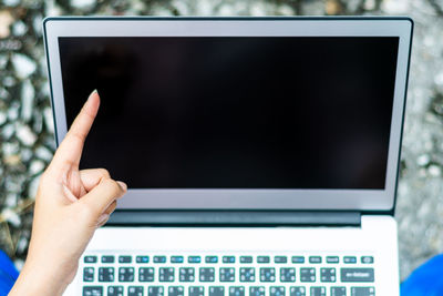 Close-up of woman pointing at laptop 