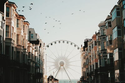 Ferris wheel amidst building against clear sky