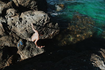 High angle view of man climbing on rock at beach