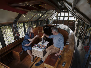 Senior couple having a candlelight dinner on a boat in boathouse clinking champagne glasses