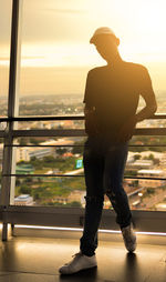 Rear view of man standing against window