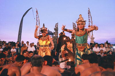 People with sculpture in background against clear sky