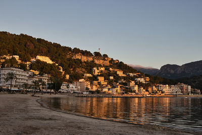 Buildings by sea against clear sky during sunset