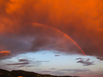 Low angle view of rainbow against cloudy sky