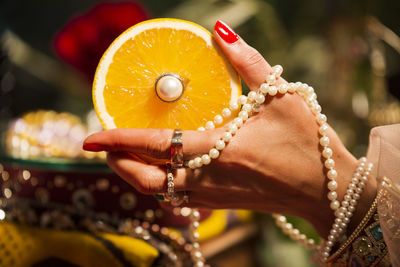 Cropped hand of woman wearing jewelry holding orange