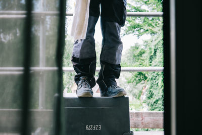 Low section of man standing in box at home