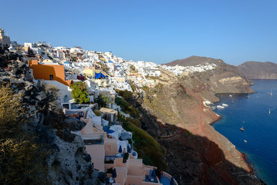 Town by sea against clear blue sky