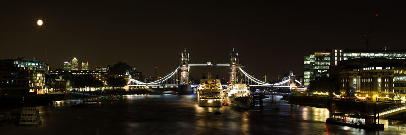 Illuminated bridge over river in city at night