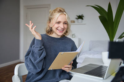 Portrait of young woman using laptop at home