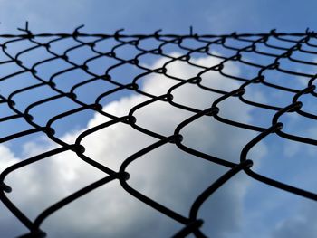 Low angle view of chainlink fence against sky