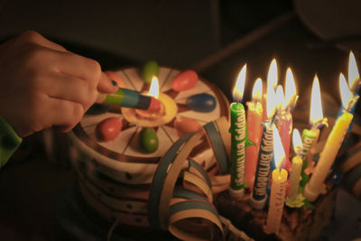 Close-up of hand holding light birthday candles with lighter