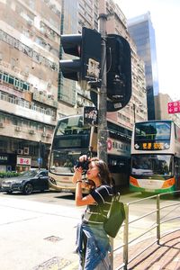Woman photographing car on street in city
