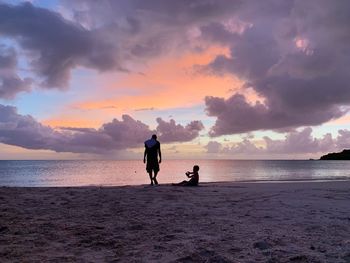 People on beach against sky during sunset